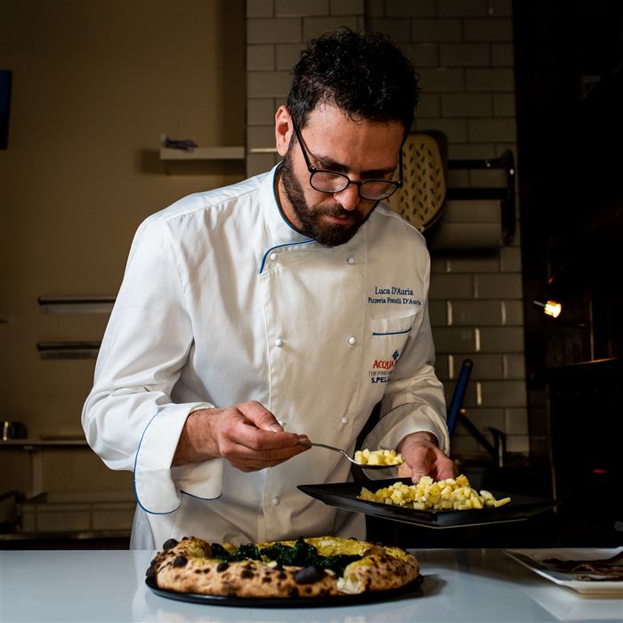 Il pizzaiolo di Fratelli D'Auria con una pizza appena sfornata